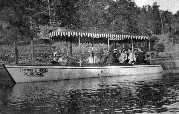 Vacationers ride on "The White Rose of Lake Mary," a small covered tour boat.