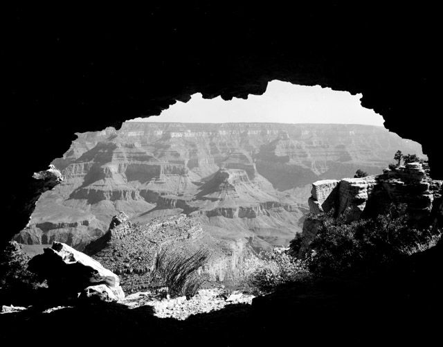 Black-and-white image of the Grand Canyon as seen through a hole in the rock