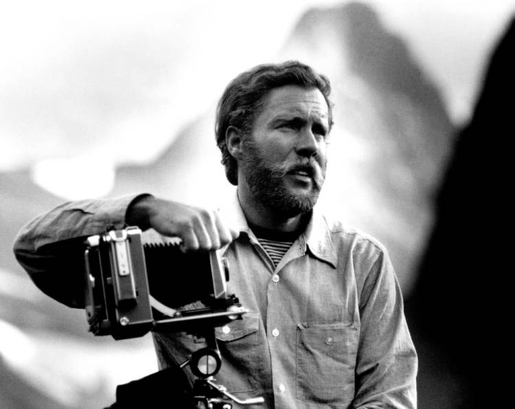 David Muench, standing with camera, with mountains in the background