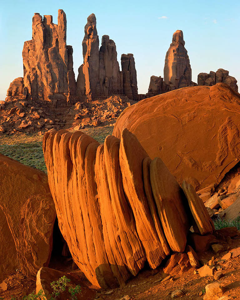 This image shows sandstone rock fins in the foreground with Yeibichai Rocks formation visible in the background in Monument Valley Navajo Tribal Park, Arizona.