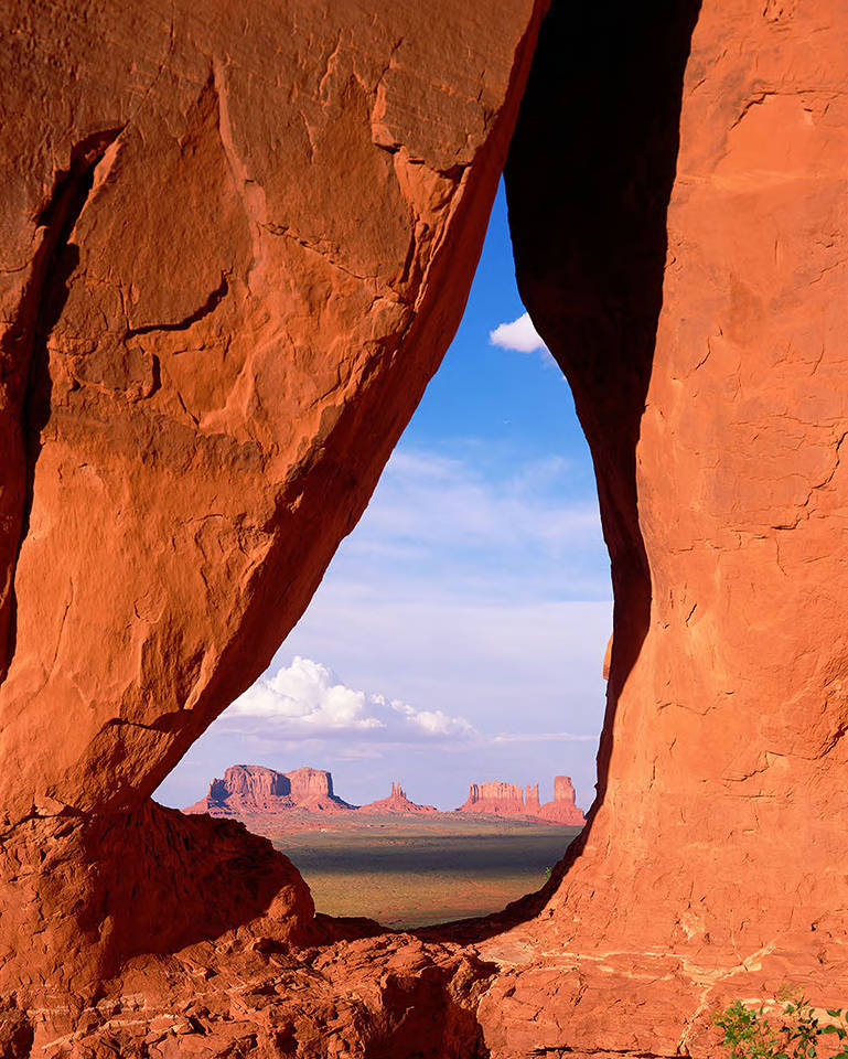 This image shows rock formations in the distance through Tear Drop Arch (alternately Teardrop Arch) in Monument Valley, Utah.