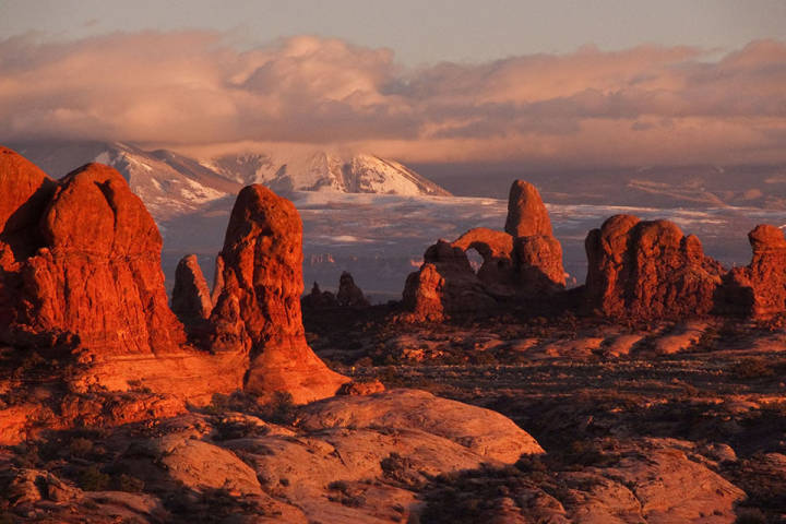 This image shows rock formations including Turret Arch in the Windows Section of Arches National Park in Utah, with the La Sal Mountains visible in the background.